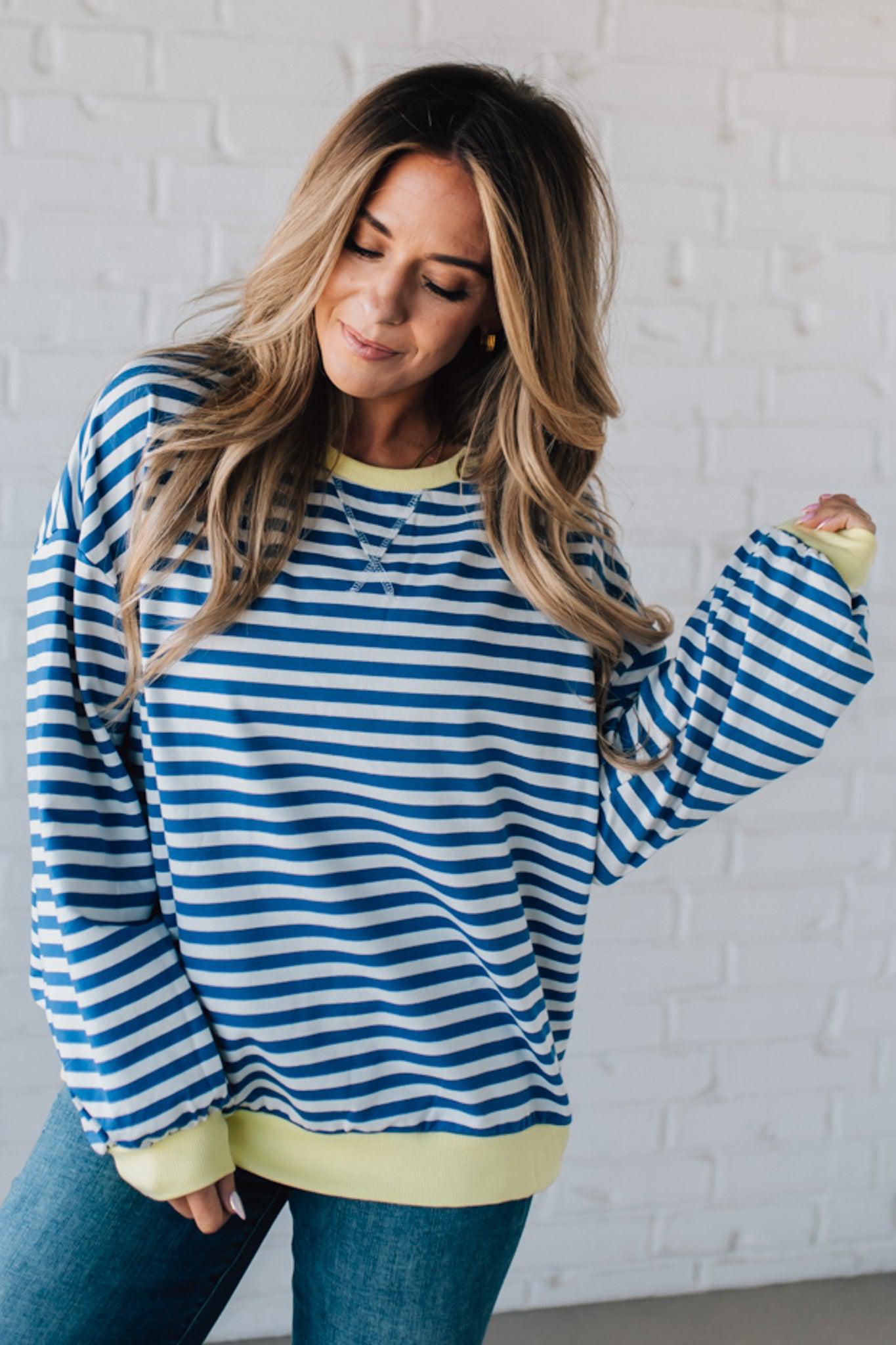 girl modeling a long sleeve oversized striped top with contrasting color on the sleeve cuff, neckline and hem