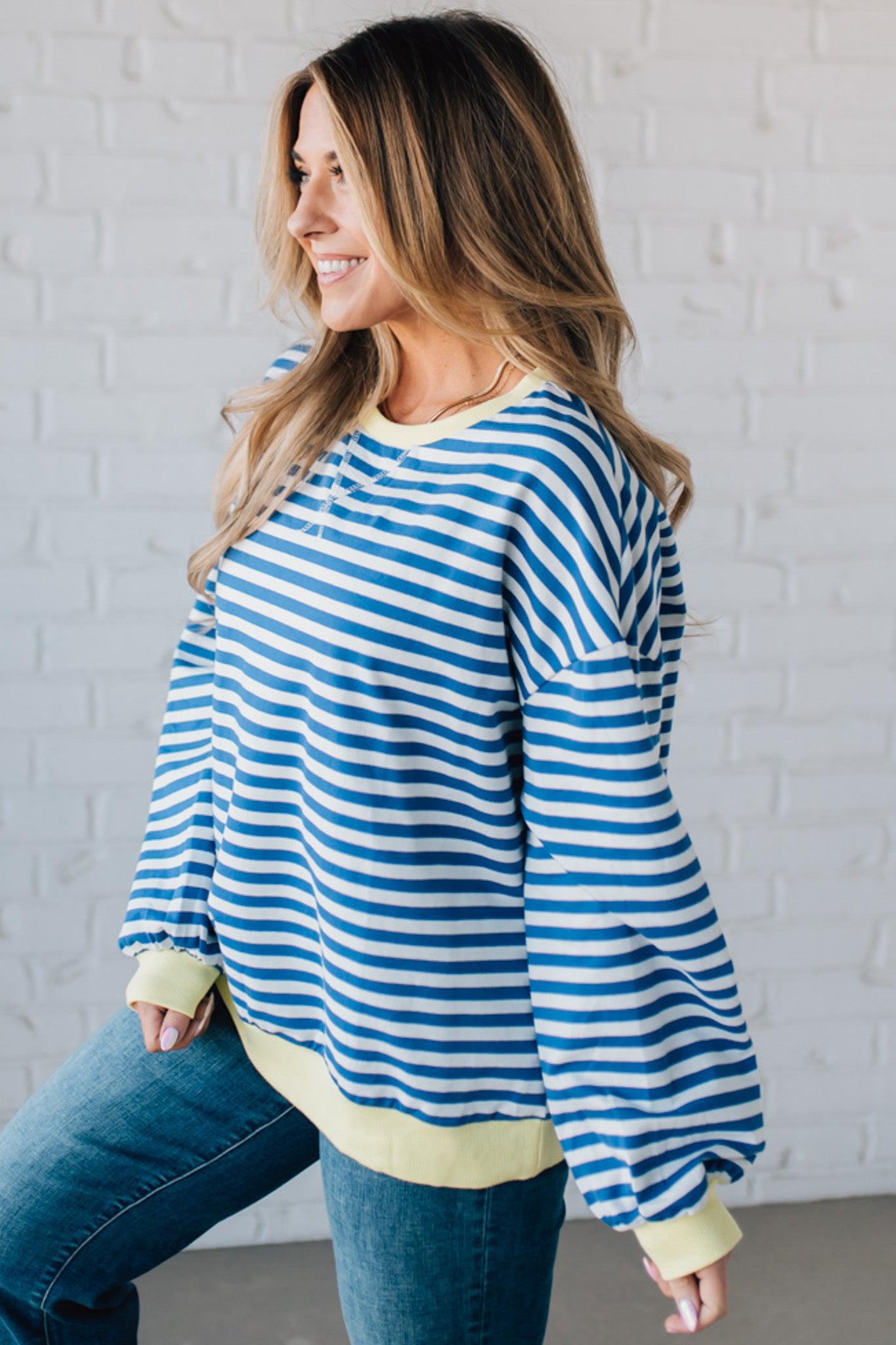 girl modeling a long sleeve oversized striped top with contrasting color on the sleeve cuff, neckline and hem