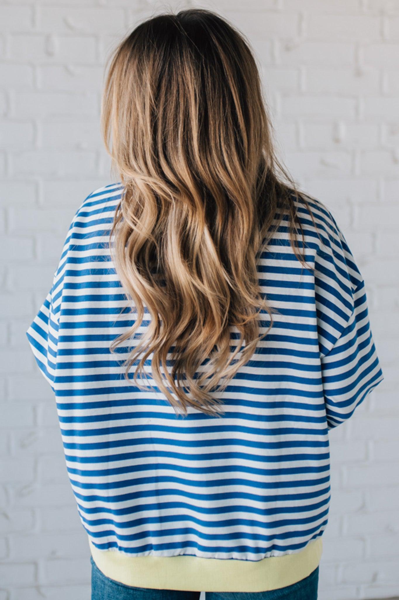 girl modeling a long sleeve oversized striped top with contrasting color on the sleeve cuff, neckline and hem