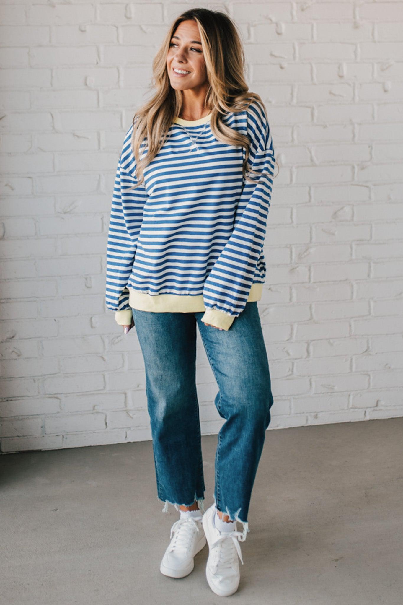 girl modeling a long sleeve oversized striped top with contrasting color on the sleeve cuff, neckline and hem