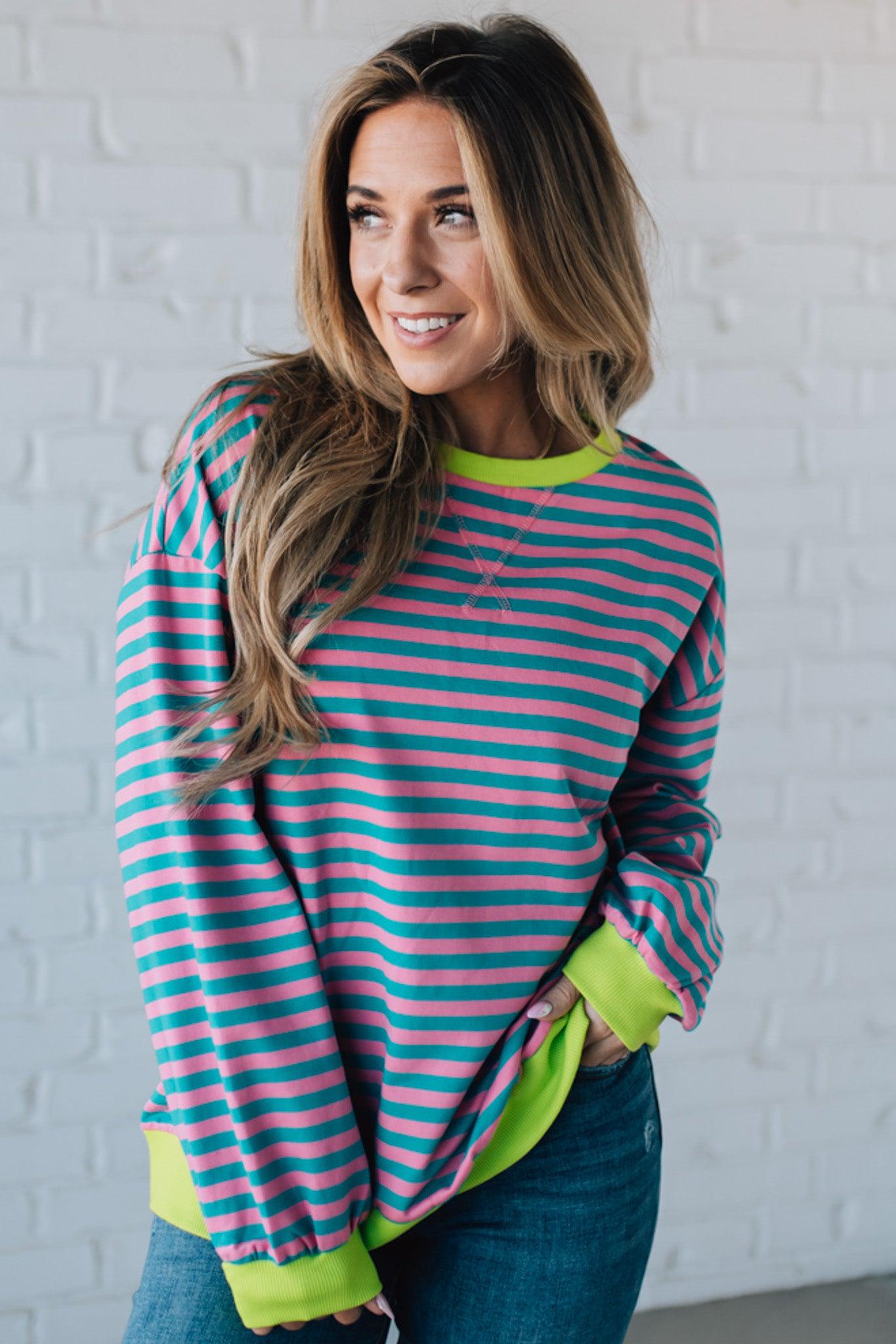 girl modeling a long sleeve oversized striped top with contrasting color on the sleeve cuff, neckline and hem