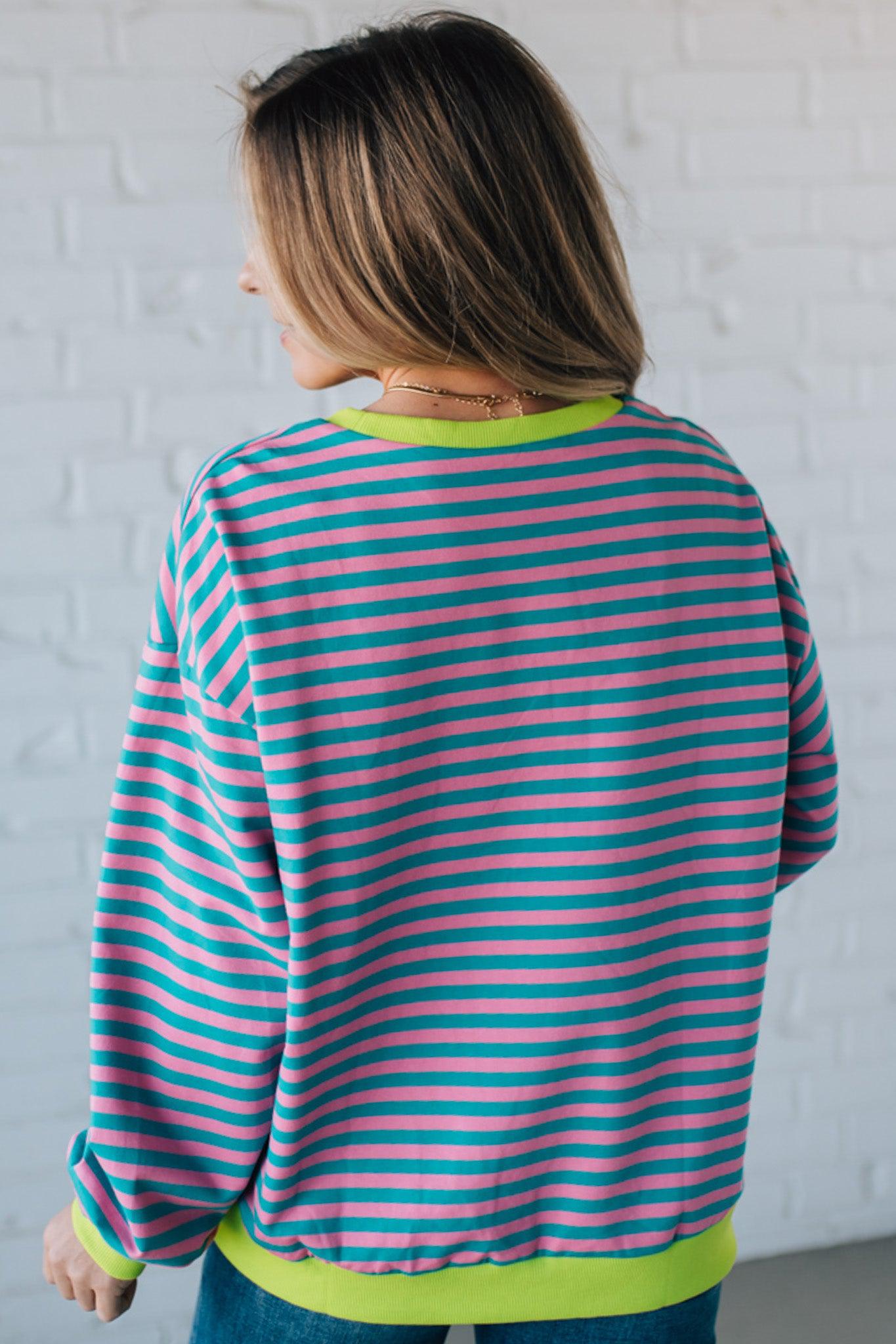 girl modeling a long sleeve oversized striped top with contrasting color on the sleeve cuff, neckline and hem