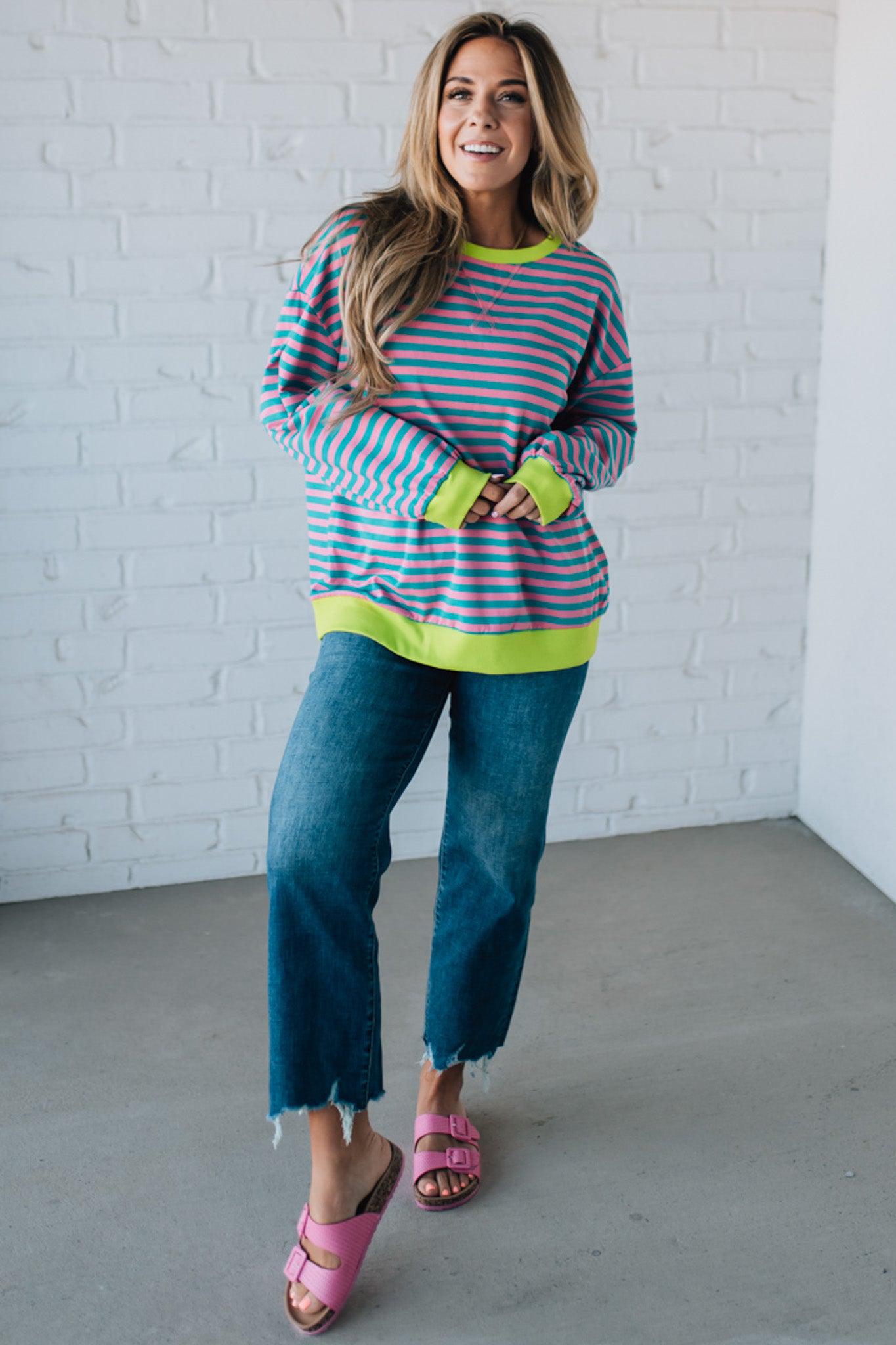 girl modeling a long sleeve oversized striped top with contrasting color on the sleeve cuff, neckline and hem