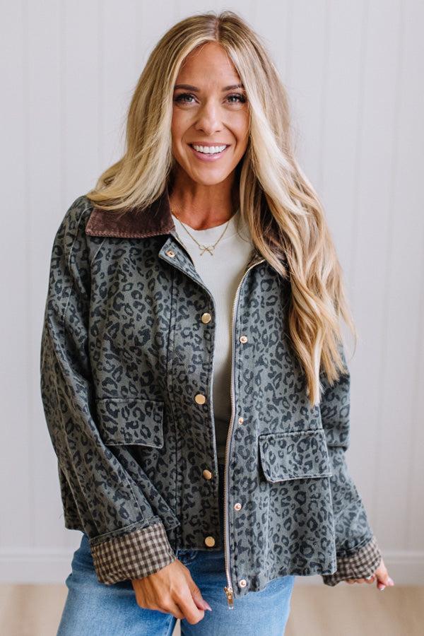 Blonde woman wearing a leopard print barn jacket with brown corduroy collar and gingham plant lining. Standing on a light wood floor with panel backdrop.
