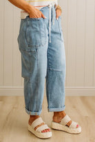 Person wearing blue jeans and white sandals on a wooden floor.