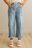 Person wearing light blue jeans and white sandals in a neutral setting