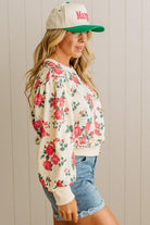Woman wearing a floral sweatshirt and cap with 'Mary' printed on it against a neutral background