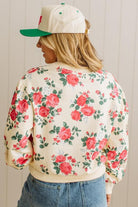 Person wearing a floral jacket and cap with a plain background