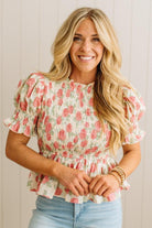 Woman wearing a floral blouse with ruffled sleeves against a plain background