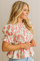 Woman wearing a floral blouse with ruffled sleeves against a neutral background