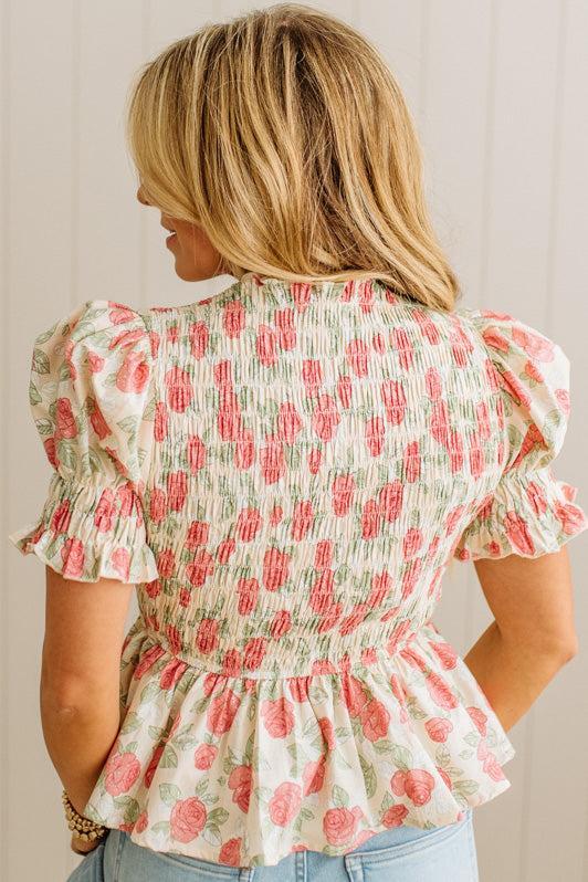 Woman wearing a floral blouse with ruffled sleeves against a neutral background