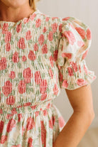 Close-up of a floral dress with ruffled sleeves on a neutral background