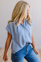 Woman wearing a light blue sleeveless shirt and jeans against a plain background