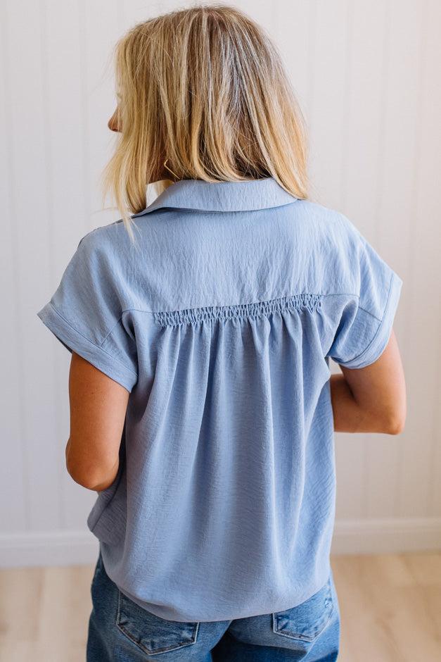 Person wearing a light blue shirt and jeans against a plain background