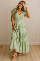 Woman wearing a light green dress with ruffled layers against a neutral background