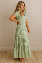 Woman wearing a light green dress against a beige wall.