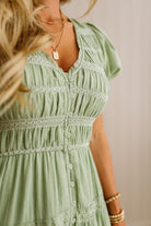 Green dress with lace details worn by a person, against a neutral background