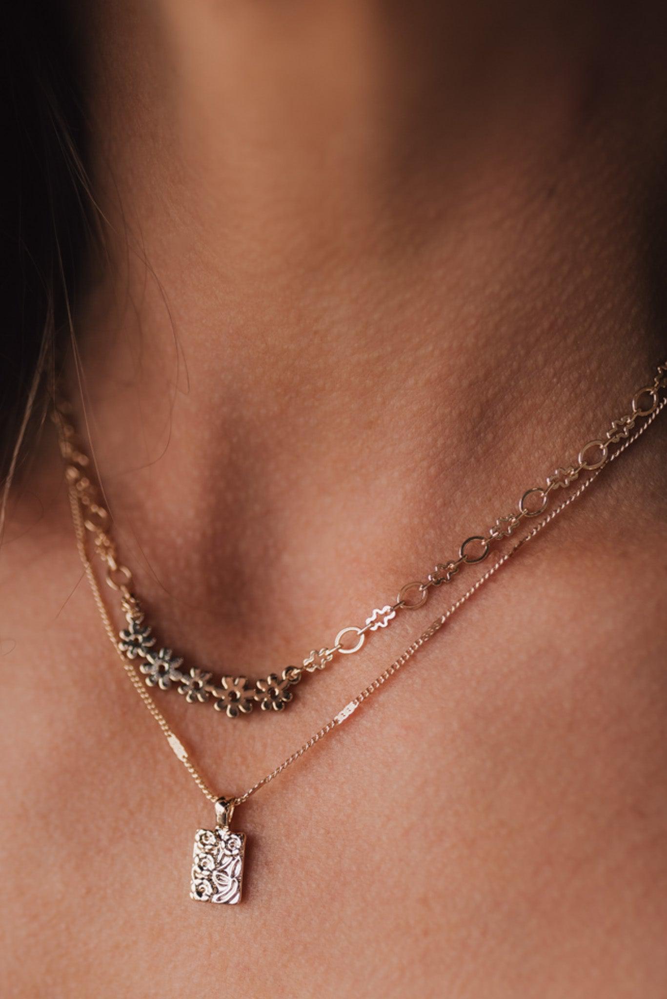 Girl modeling a gold necklace that has two layers with dainty floral details