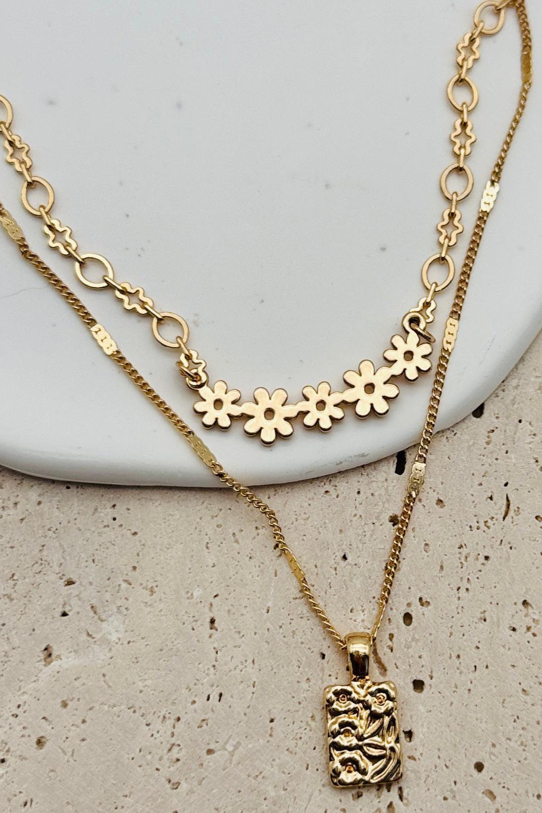 Flat lay of a gold necklace that has two layers with dainty floral details