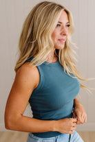 Woman wearing a blue sleeveless top against a neutral background