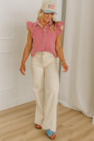 Woman wearing a red and white striped shirt, beige pants, and a cap with an American flag design.
