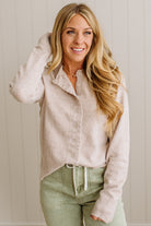 Woman wearing a light-colored jacket and green pants against a neutral background