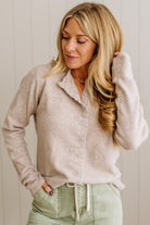 Woman wearing a beige cardigan and light green pants against a white background