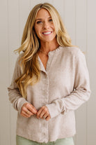 Woman wearing a beige button-up shirt against a light background
