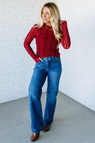 Woman wearing a red mesh lace top against a white background