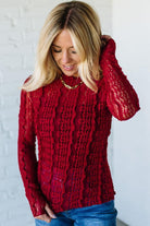 Woman wearing a red mesh lace top against a white background