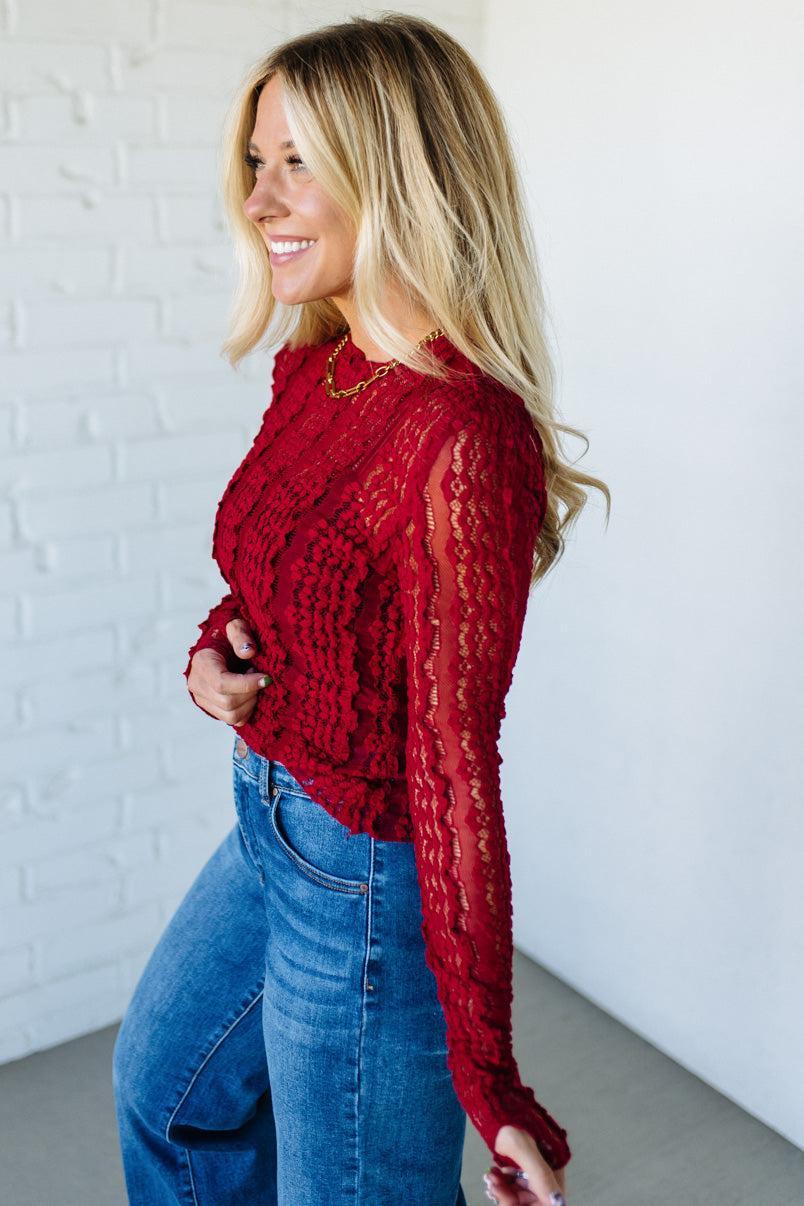 Woman wearing a red mesh lace top against a white background