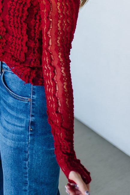 Woman wearing a red mesh lace top against a white background