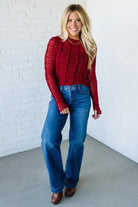 Woman wearing a red mesh lace top against a white background