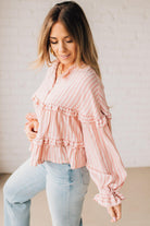 BLONDE WOMAN WEARING A VARIEGATED STRIPE FLOWY BOHO TOP WITH BUTTONED PLACKET.