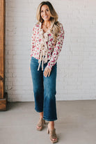 blonde girl modeling a long sleeve cream colored cardigan with a pink floral pattern and ruffle edge detail