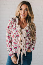 blonde girl modeling a long sleeve cream colored cardigan with a pink floral pattern and ruffle edge detail