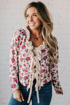 blonde girl modeling a long sleeve cream colored cardigan with a pink floral pattern and ruffle edge detail