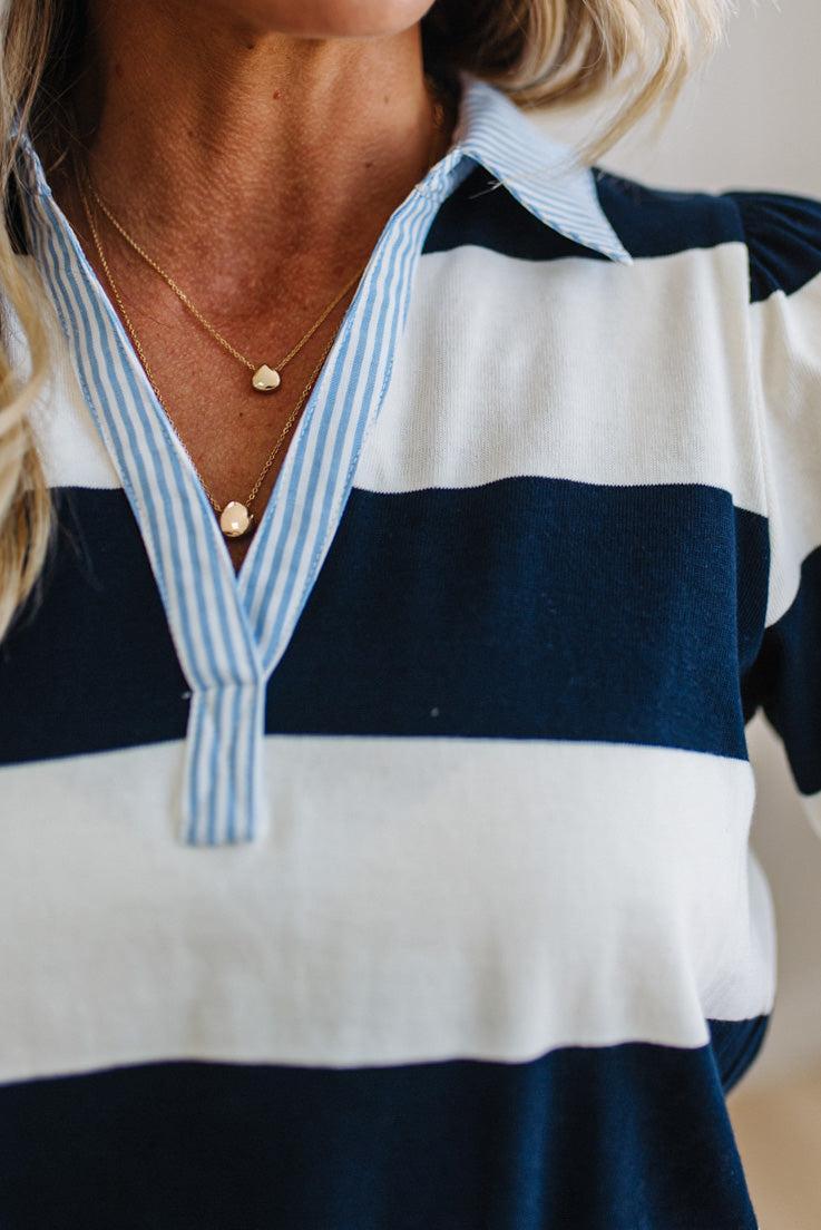 Close-up of a person wearing a navy and white striped shirt with a blurred background