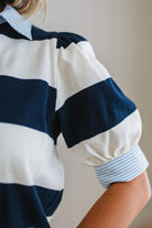 Woman wearing a navy and white striped shirt with a plain background