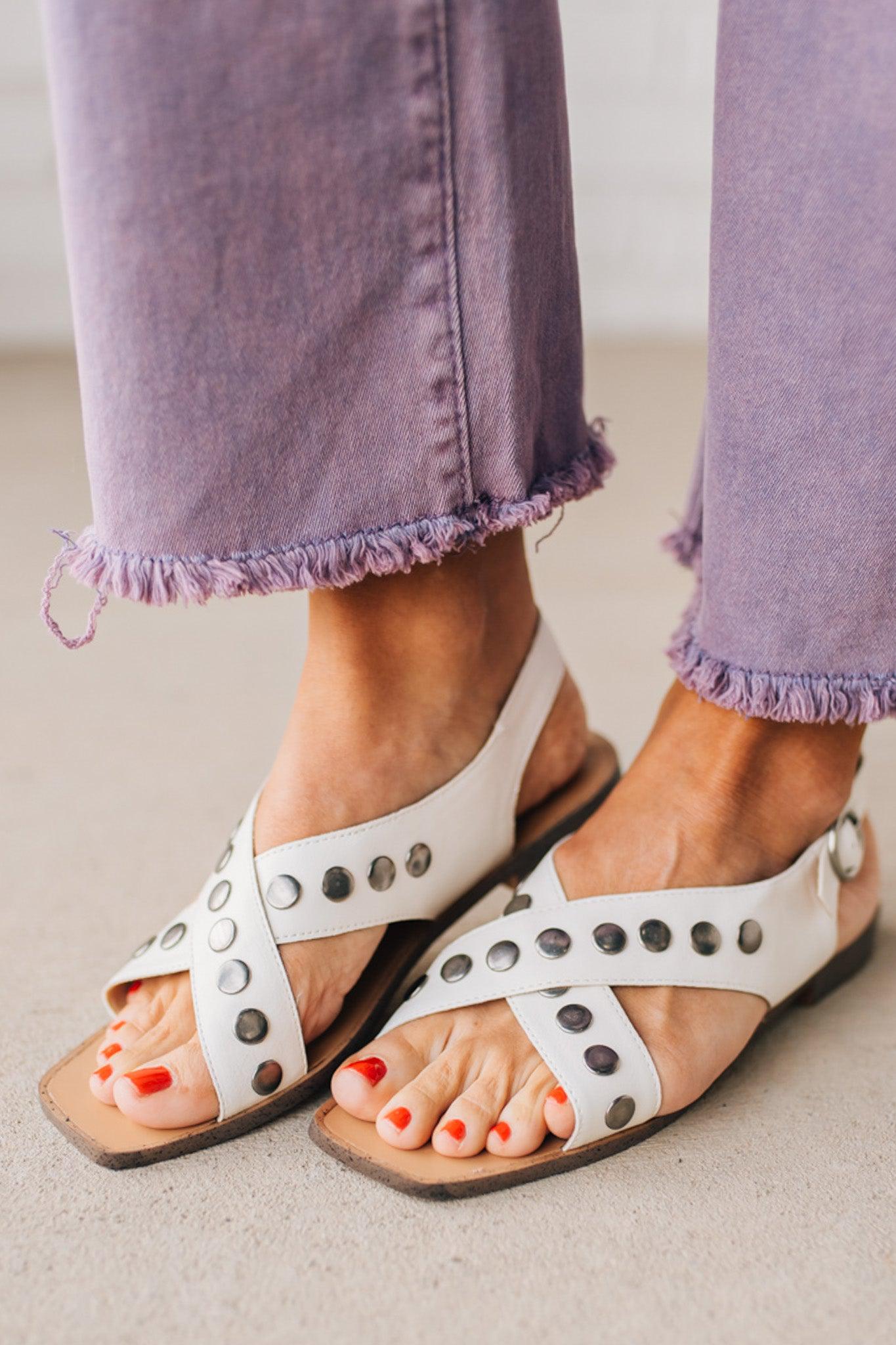 White faux leather sandals with features of metal studded embellishments on both straps, and a square cut toe.