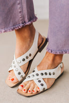 White faux leather sandals with features of metal studded embellishments on both straps, and a square cut toe.