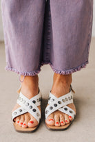 White faux leather sandals with features of metal studded embellishments on both straps, and a square cut toe.