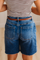 Person wearing a striped shirt and blue denim shorts with a blurred background
