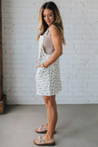 Blonde Woman Wearing a Stretch Ditsy Print Denim Overall Mini Dress in Cream and multi color flowers.