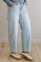 Person wearing light blue jeans and white sneakers on a wooden floor.