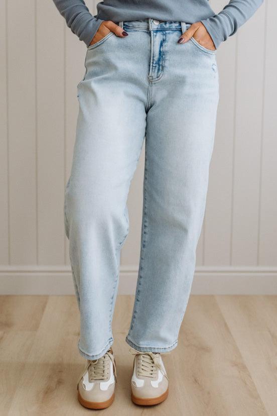 Person wearing light blue jeans and a gray sweater against a neutral background