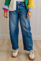 Person wearing blue jeans and a colorful sweater with a neutral background