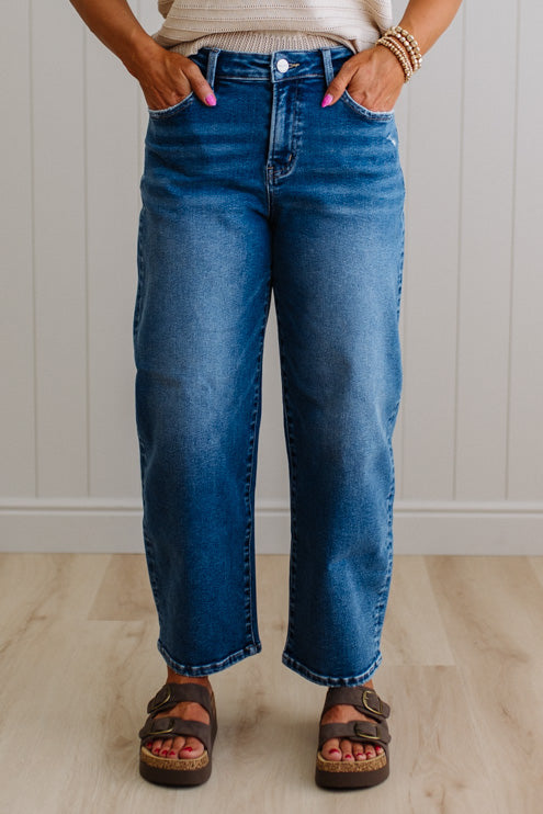 Person wearing blue jeans standing against a white paneled wall.