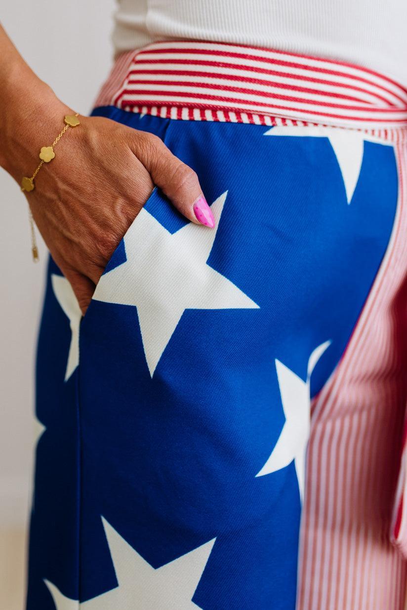 Person wearing blue star pants with white stars, holding a red and white striped fabric.