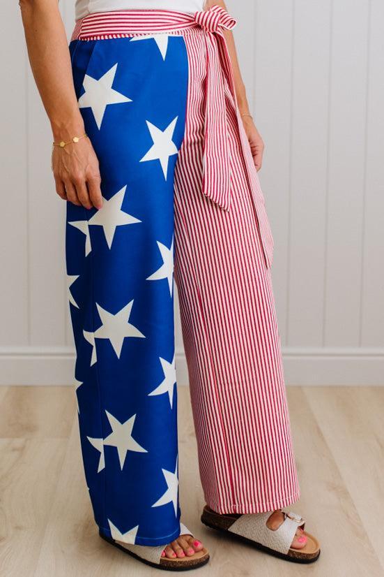 Person wearing blue pants with white stars and pink striped pants indoors.